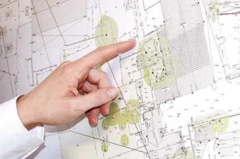 Vermessungsleistung - Bestandspläne / Plangrundlage Das Bild zeigt eine Hand, die auf einen Bestandplan zeigt